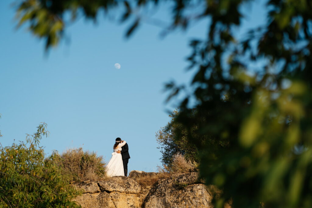 Photo of a couple in Sicily on a hill in the Valley of the Temples with the moon in the background