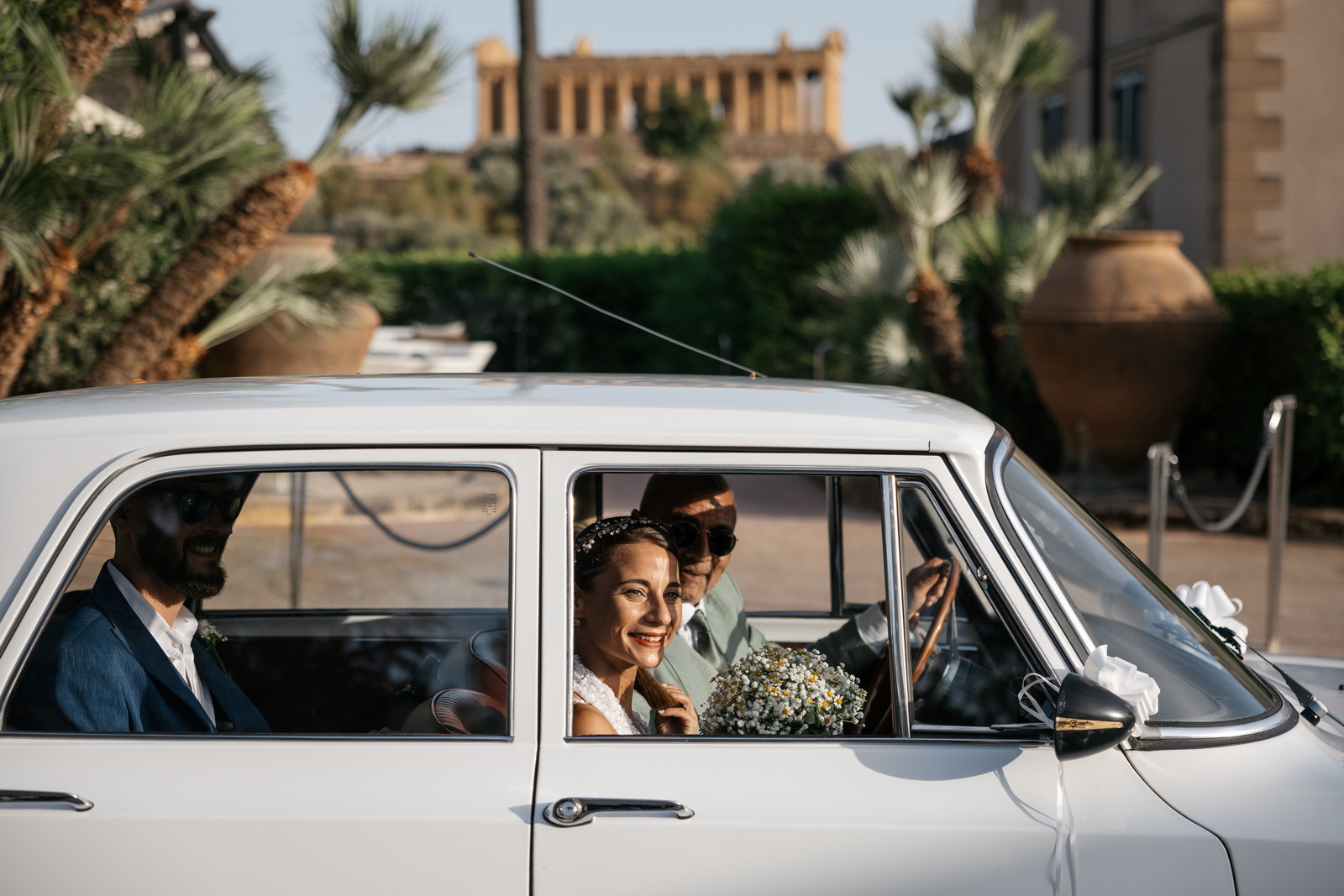 Image of a bride in a vintage car with the Temple of Concordia Agrigento in the background