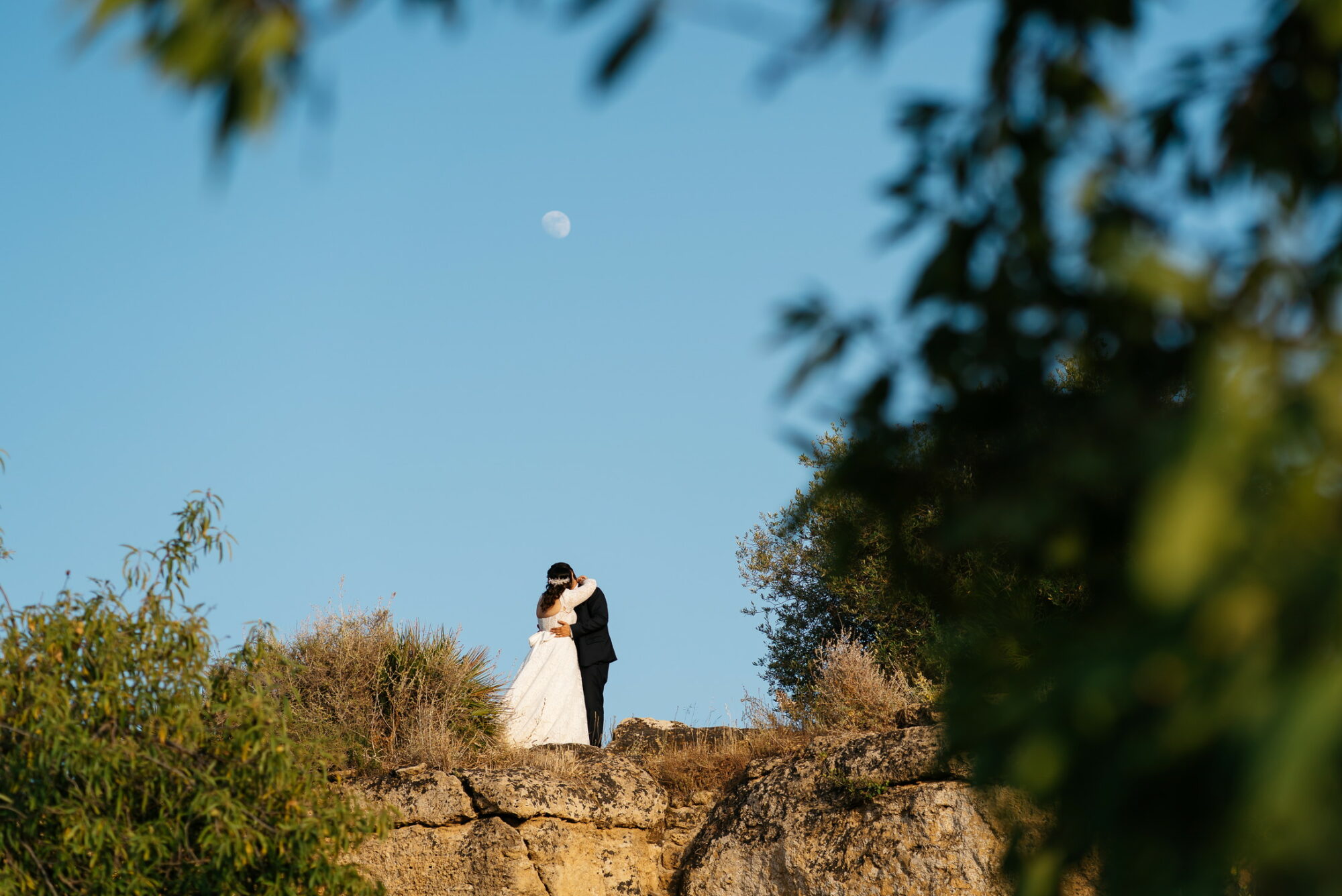 Photo of a couple in Sicily on a hill in the Valley of the Temples with the moon in the background