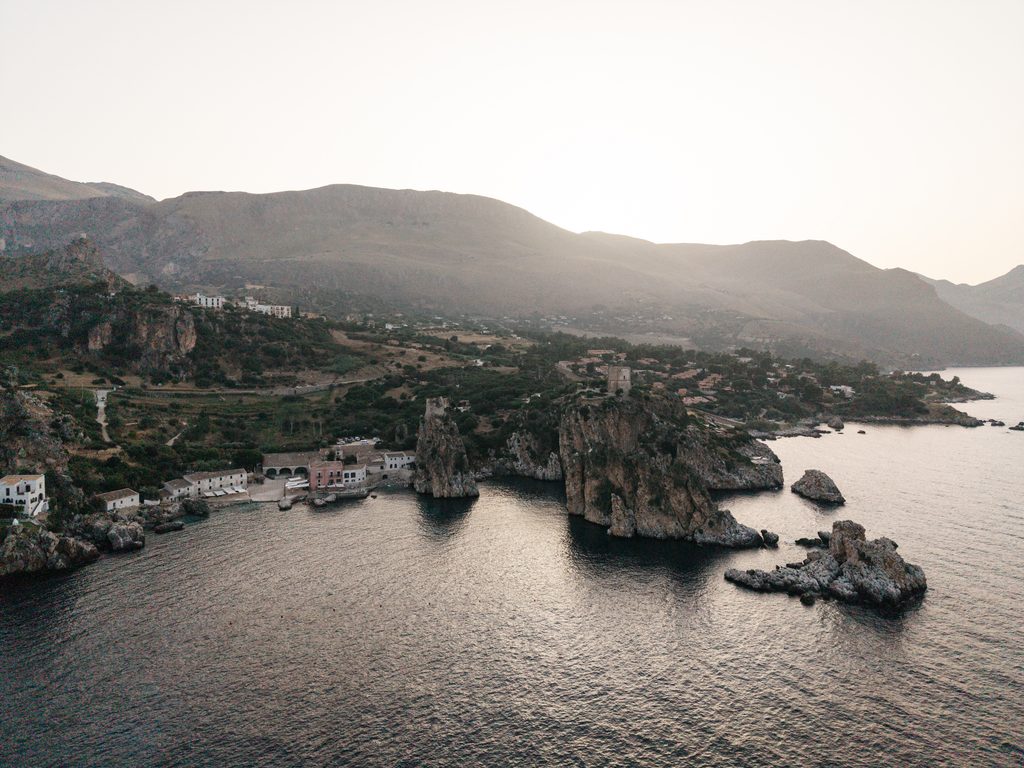 Aerial view of Tonnara di Scopello, the sea stacks and the mountains behind Scopello in the evening