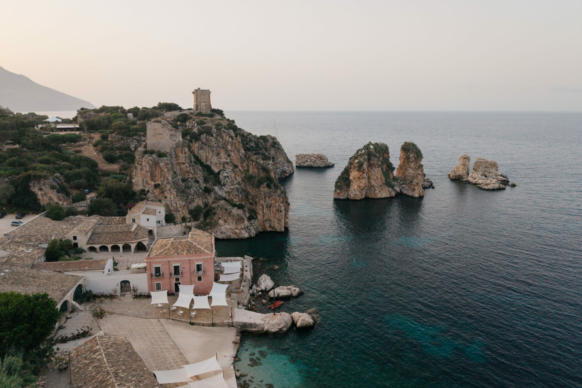 Aerial view of Tonnara di Scopello, the sea stacks and the mountains behind Scopello in the evening