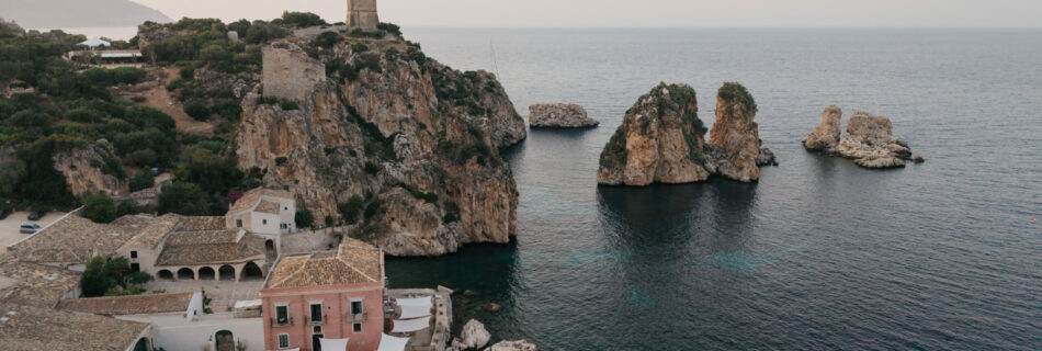 Aerial view of Tonnara di Scopello, the sea stacks and the mountains behind Scopello in the evening