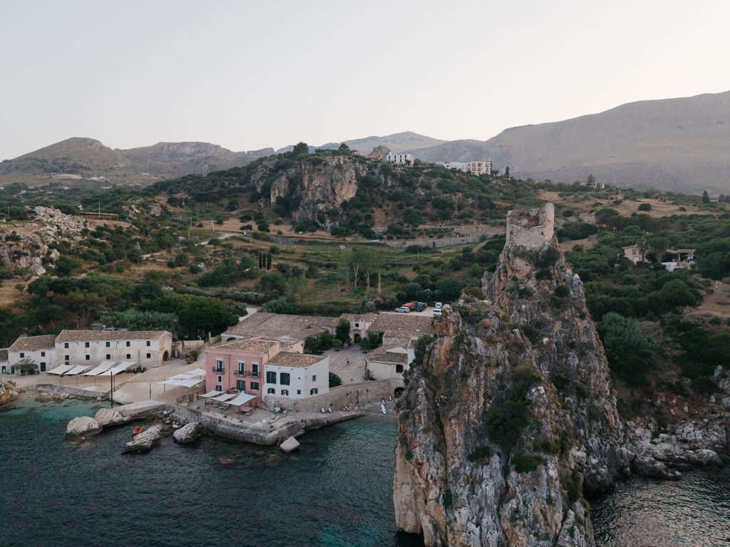 Close aerial view of Tonnara di Scopello with its historic buildings and tower on the rock