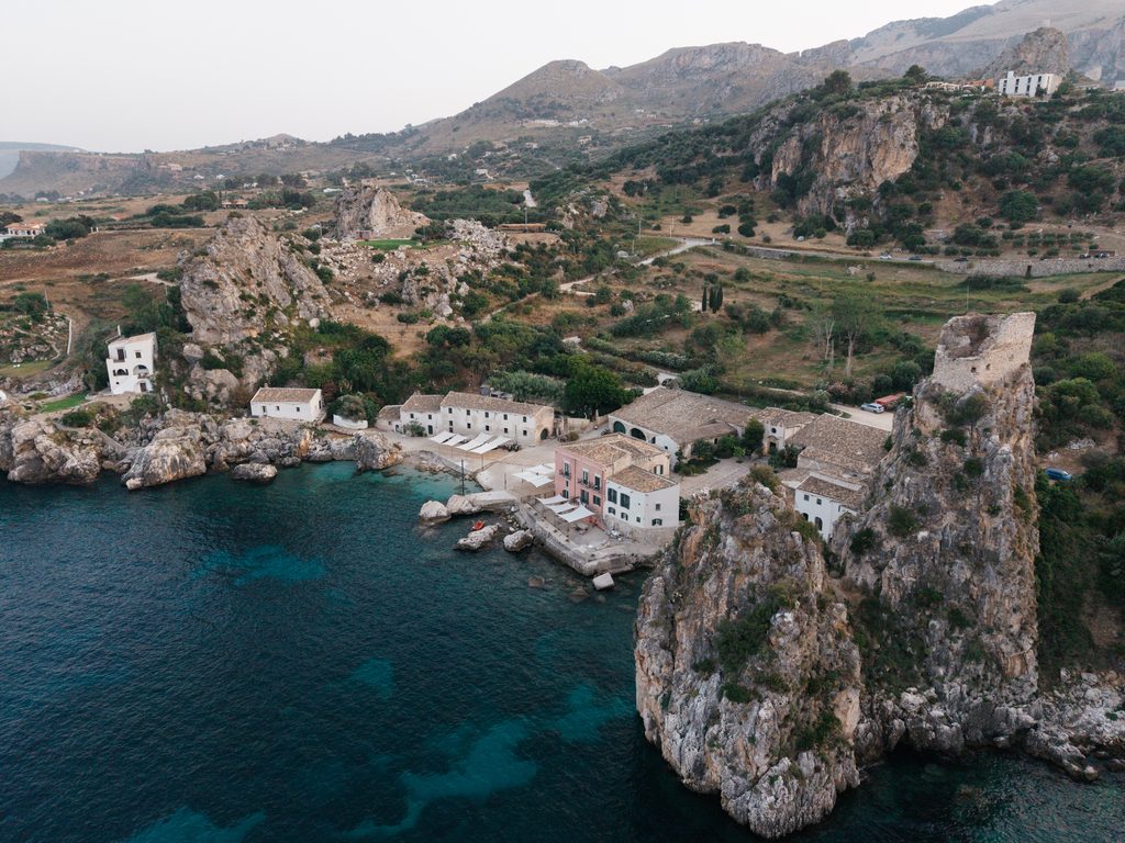 Aerial view of Tonnara di Scopello between the rocky coastline and the surrounding hills