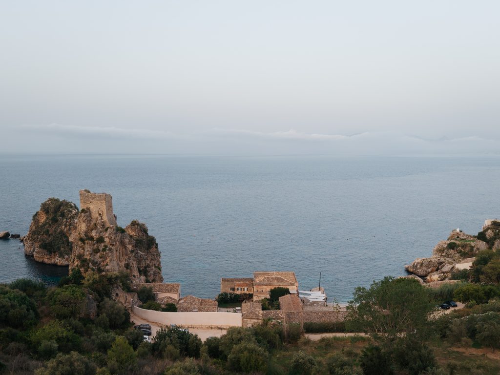 Tonnara di Scopello seen from inland towards the sea with the historic tower on the rock